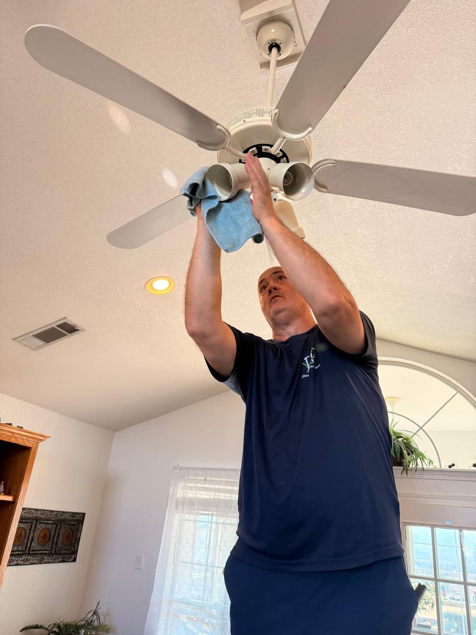 Crew member cleaning a ceiling fan